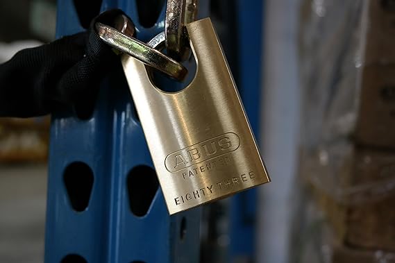 close up of an Abus brass closed shackle padlock attached to a chain