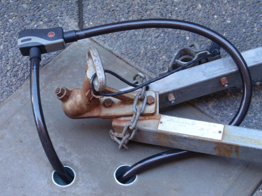 Anka-U solid metal in ground security anchor shown concreted in place with alarm cable lock around trailer